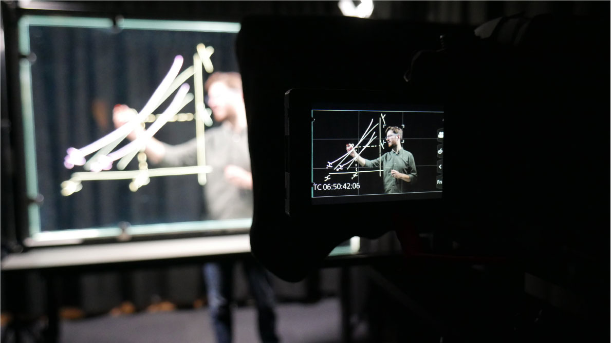 Close up of camera feed on University professor drawing on clear glass whiteboard