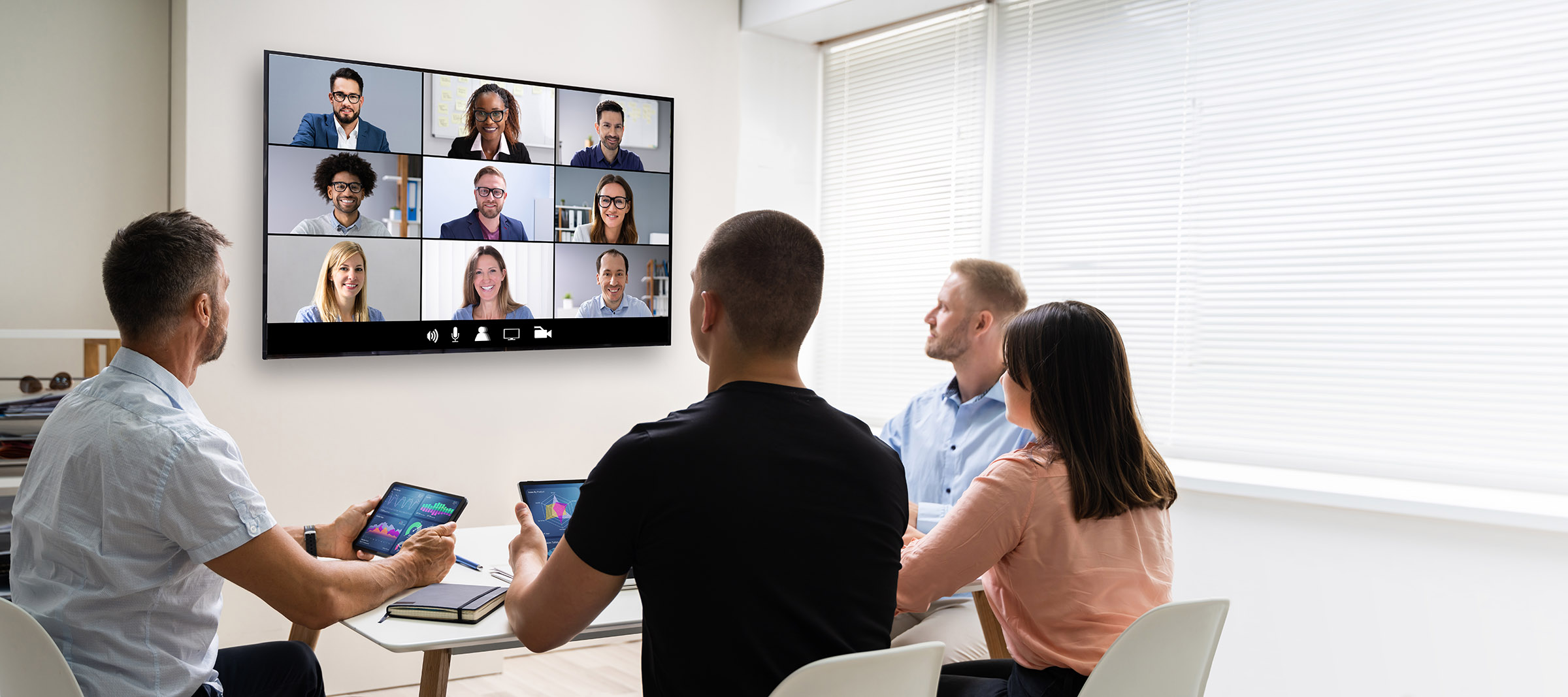 group of professionals in a modern workplace on a video call with remote colleagues